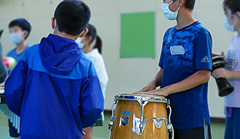 小学校へのアウトリーチの写真3。打楽器を小学生が叩いている。
